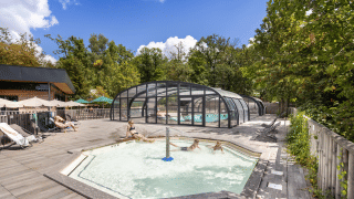 Zona de piscina exterior con piscina cubierta y jacuzzi en Huttopia Versailles, Île de France, Francia.