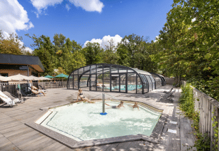Outdoor pool area with a covered swimming pool and hot tub at Huttopia Versailles in Île de France, France.