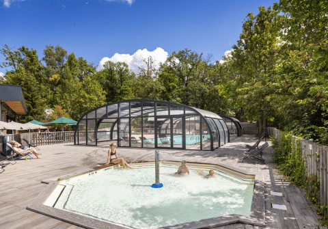 Piscine all'aperto e ospiti rilassati circondati dalla natura al villaggio Huttopia Versailles, Île de France.