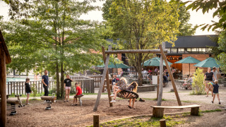 Kinder spielen auf einem Spielplatz mit Schaukel im Ferienpark Huttopia Versailles, Île de France, Frankreich.