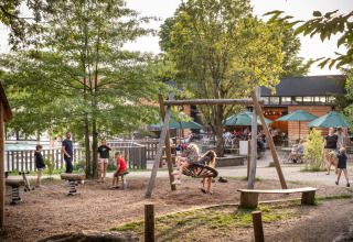 Kinderen spelen op een schommel bij vakantiepark Huttopia Versailles in Île de France, Frankrijk, met ouders nabij.