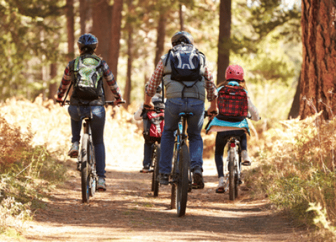 Gezin op fietstocht in het bos bij Huttopia Versailles vakantiepark, Île de France, Frankrijk.