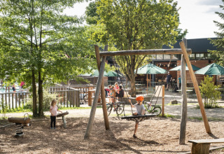 Kinderen spelen op het speelplein van Huttopia Versailles vakantiepark, omringd door groen in Île de France.
