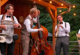Et jazzband optræder udendørs om aftenen på Huttopia Versailles feriepark i Île de France, Frankrig.