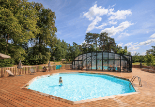 Piscine extérieure avec terrasse en bois et parasols au parc de vacances Huttopia De Meinweg à Limbourg, Pays-Bas.