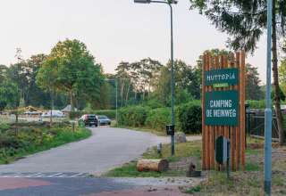 Eingang zum Campingplatz Huttopia De Meinweg in Limburg, Niederlande, mit Autos und grünem Schild.