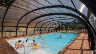 Piscina cubierta con familias disfrutando en Huttopia De Meinweg, un parque vacacional de Limburg, Países Bajos.