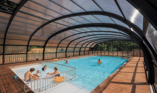 Piscina cubierta con familias disfrutando en Huttopia De Meinweg, un parque vacacional de Limburg, Países Bajos.