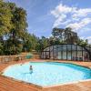 Outdoor swimming pool with wooden deck and covered pool area at Huttopia De Meinweg holiday park, Limburg, Netherlands.