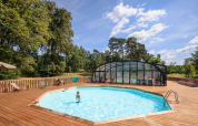 Udendørs swimmingpool med trædæk og overdækket poolområde på Huttopia De Meinweg feriepark, Limburg, Holland.