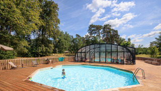 Buitenzwembad met houten terras en overdekt gedeelte bij Huttopia De Meinweg vakantiepark, Limburg, Nederland.