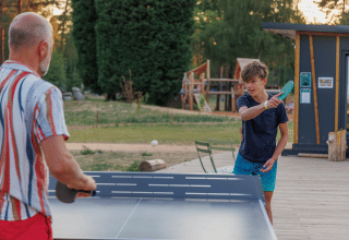 A man and a boy play table tennis outdoors at Huttopia De Meinweg holiday park in Limburg, Netherlands.