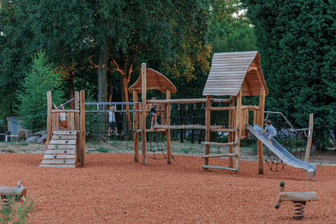 Legeplads med træ-legetårn og rutchebane i ferieparken Huttopia De Meinweg, Limburg, Nederlandene.