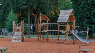 Parque infantil con estructura de madera y tobogán en Huttopia De Meinweg, Limburg, Países Bajos.