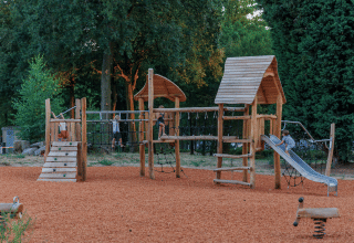 Spielplatz mit Holzturm und Rutsche im Ferienpark Huttopia De Meinweg, Limburg, Niederlande.