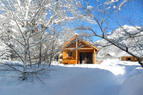 Cabaña de madera rodeada de nieve en Les Chalets Huttopia de Vallouise, Provenza-Alpes-Costa Azul, Francia.