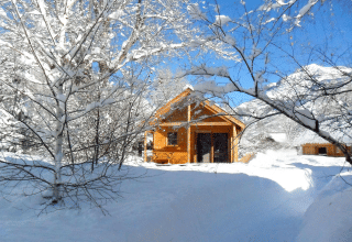 Chalet en bois entouré de neige aux Chalets Huttopia de Vallouise, Provence-Alpes-Côte d’Azur, France.