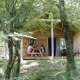 To personer sidder ved et bord foran Chalet Montana i Huttopia Vallouise, Frankrig, omgivet af grønne træer.