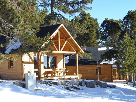 Houten chalets in een winters bos bij Les Chalets Huttopia de Font-Romeu, vakantiepark in Occitanië, Frankrijk.