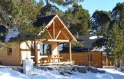 Houten chalets in een winters bos bij Les Chalets Huttopia de Font-Romeu, vakantiepark in Occitanië, Frankrijk.