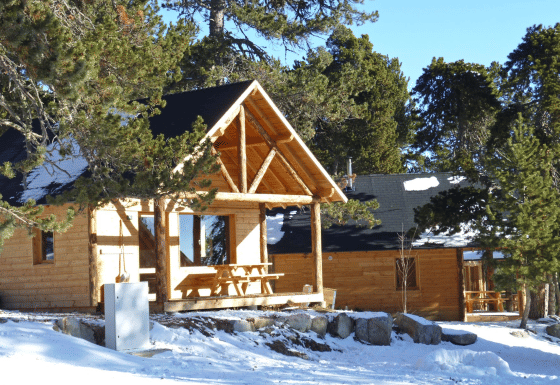 Holzchalets im verschneiten Wald bei Les Chalets Huttopia de Font-Romeu, Ferienpark in Occitanie, Frankreich.
