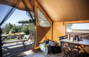 Vista desde una tienda safari Canadienne en Huttopia Versailles, con mesa puesta y picnic exterior.