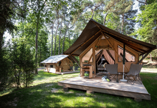 Tiendas safari con terraza de madera en un bosque verde en el camping Huttopia Versailles, Francia
