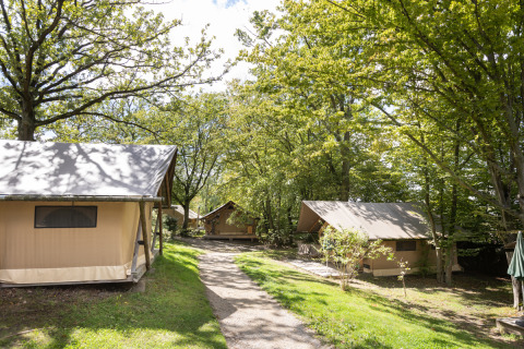 Tende safari immerse tra gli alberi a Huttopia Versailles in Francia, atmosfera da campeggio tranquilla.