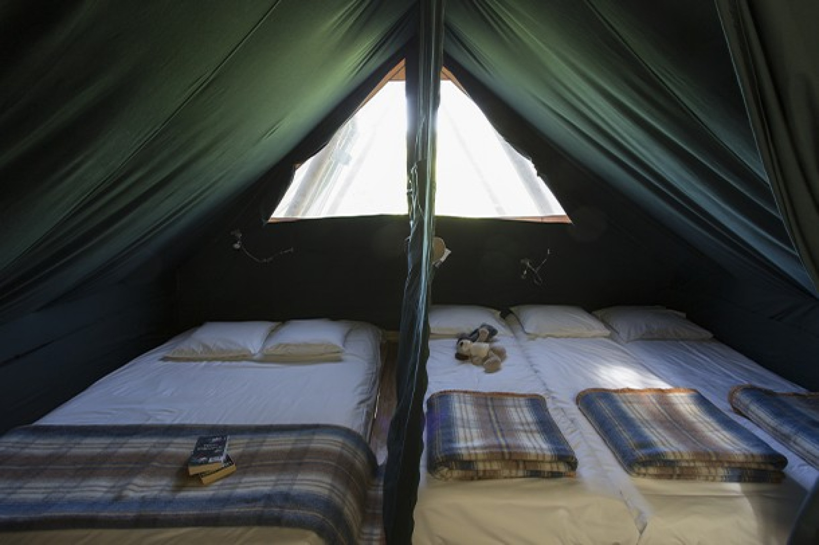 Interieur van de Cahutte bij Huttopia Versailles in Frankrijk met twee bedden en een warme sfeer.