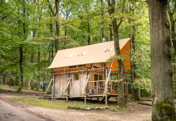 Cabane Cahutte à Huttopia Versailles en France, entourée par la forêt verdoyante et des sentiers boisés.