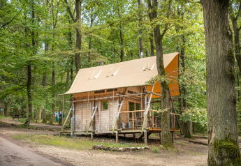Cahutte-Hütte bei Huttopia Versailles, Frankreich, umgeben von üppigem grünen Wald und Wegen.
