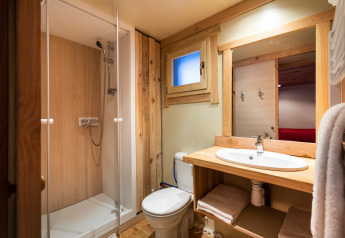 Badkamer bij een glamping-accommodatie met douche, toilet, houten details en een moderne wastafel.