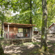 Træhytte ved navn Chalet Evasion i grøn skov ved Huttopia Versailles, Frankrig, med terrasse og stole.