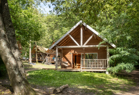Blokhut The cabin tussen groene bomen, met veranda en een rustgevende sfeer in het bos.