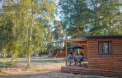 Familie nyder udendørs ophold ved Chalet Evasion i Huttopia De Meinweg, omgivet af træer og natur.