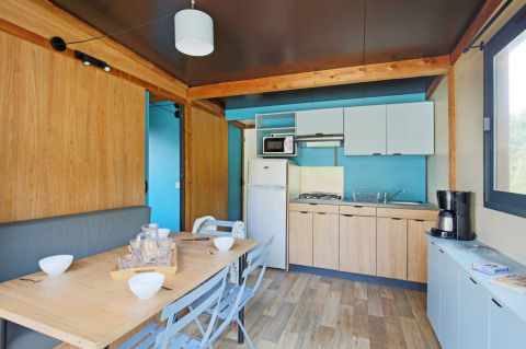 Moderne køkken og spisestue i Chalet Evasion på Huttopia De Meinweg, Nederlandene, med træmøbler.