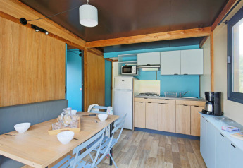 Moderne keuken en eetruimte in Chalet Evasion bij Huttopia De Meinweg, Nederland, met houten elementen.