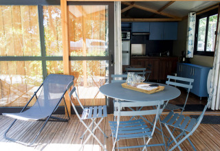 Terraza con muebles de exterior azules y una tumbona en Chalet Evasion, Huttopia De Meinweg, Países Bajos.