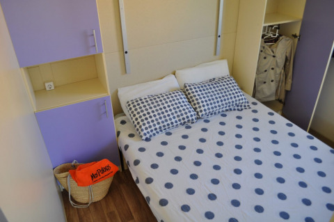 Dormitorio del Bungalow Morea en Camping Mas Patoxas, España, con cama doble y armarios morados.