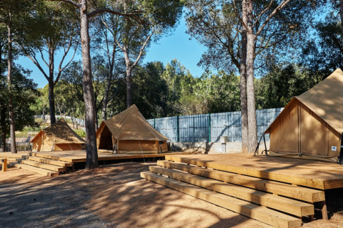 Glamping Nature Tent al Camping Mas Patoxas in Spagna con grandi tende teepee su piattaforme di legno tra gli alberi.