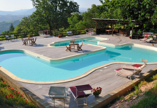 Poollandschaft mit Liegestühlen im Freien bei Camping Casa Tartufo im Grünen in Marche, Italien.