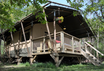 Safaritent Wood Lodge bij Camping Casa Tartufo in Italië, omgeven door bomen en natuur.