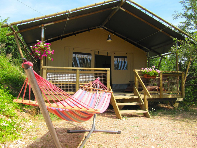 Außenaufnahme eines Safari-Zeltes namens Wood Lodge mit bunter Hängematte und Blumen auf der Veranda.