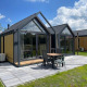 Lille, moderne tiny house med træ- og glasfacade på Camping Si-Es-An i Holland, udendørs terrasse.