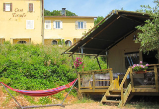 Blokhut, hangmat en hoofdgebouw op Camping Casa Tartufo vakantiepark in Marche, Italië.