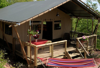 Een glamping tent met veranda en hangmat omgeven door natuur op Camping Casa Tartufo in Marche, Italië.