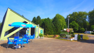 Zona de cafetería al aire libre con sillas azules en Camping Seasonova Le Martinet en Centre-Val de Loire, Francia.