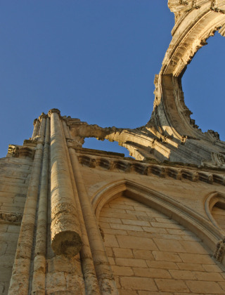 Ruinas de una iglesia de piedra antigua con arcos y techo destruido bajo el cielo azul cerca de Briare-le-Canal, Francia.