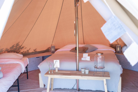Innenansicht eines luxuriösen Zeltes mit Doppelbett und Sitzecke im Little Canvas Escape, Friesland.