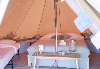 Innenansicht eines luxuriösen Zeltes mit Doppelbett und Sitzecke im Little Canvas Escape, Friesland.